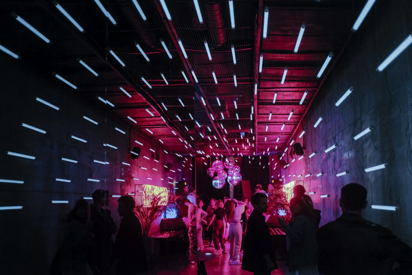Público reunido em uma pista de dança com iluminação de festa